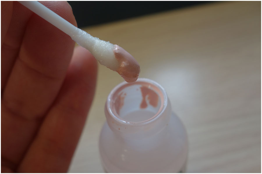 Showing the steps of application. The first picture shows the cotton bud dipped in the pink solution, the second photo shows the drying lotion applied on the back of my hand and how it dries over five minutes to become like a clay mask texture