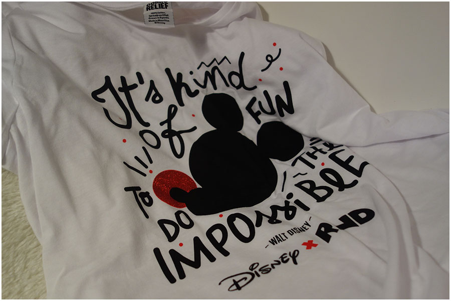 A white Disney T-shirt with a silhouette of Mickey with a red nose. It has the quote 'It's kind of fun to do the impossible" around the picture
